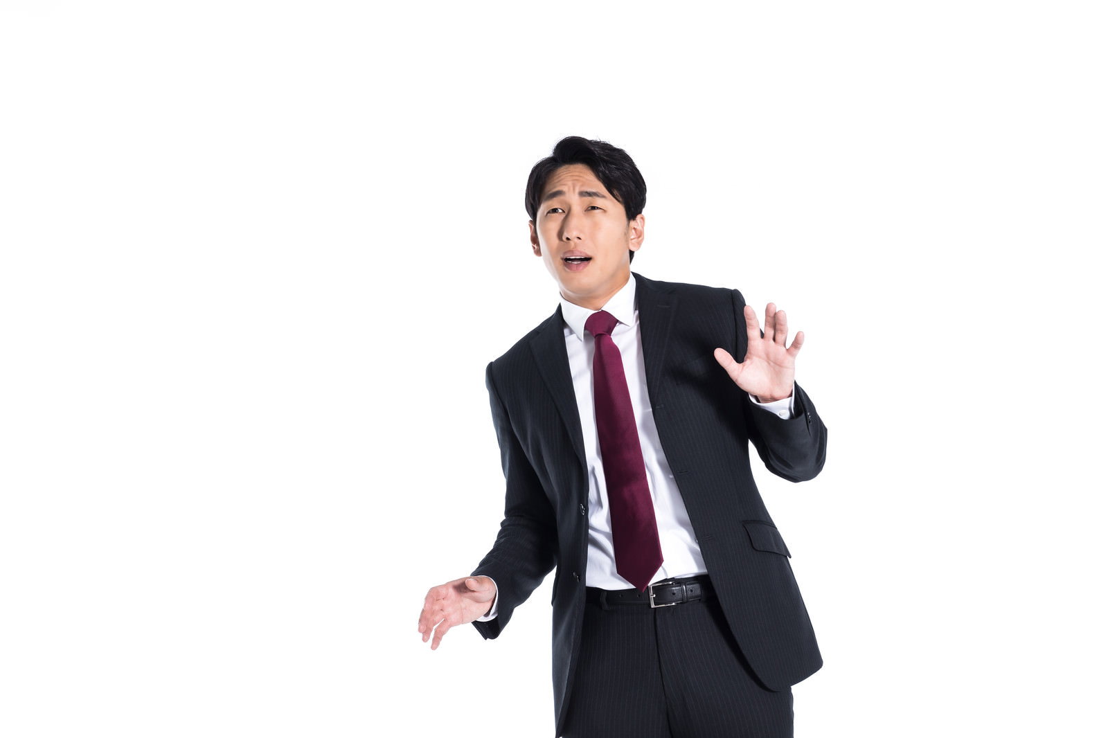 黒いストライプスーツの男性が両手を広げて上を向き、困惑した表情で戸惑っている［モデル：大川竜弥］