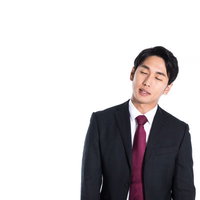 立ちながら寝落ち寸前のダークスーツ姿の営業マンの写真