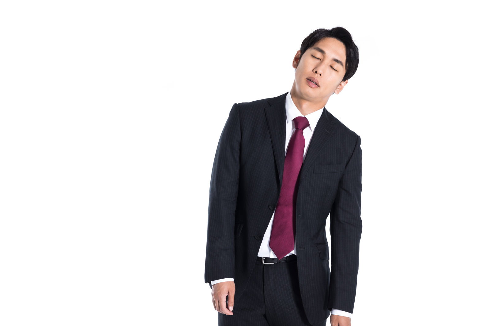 赤いネクタイのスーツ姿の男性が立ったまま居眠りしている［モデル：大川竜弥］