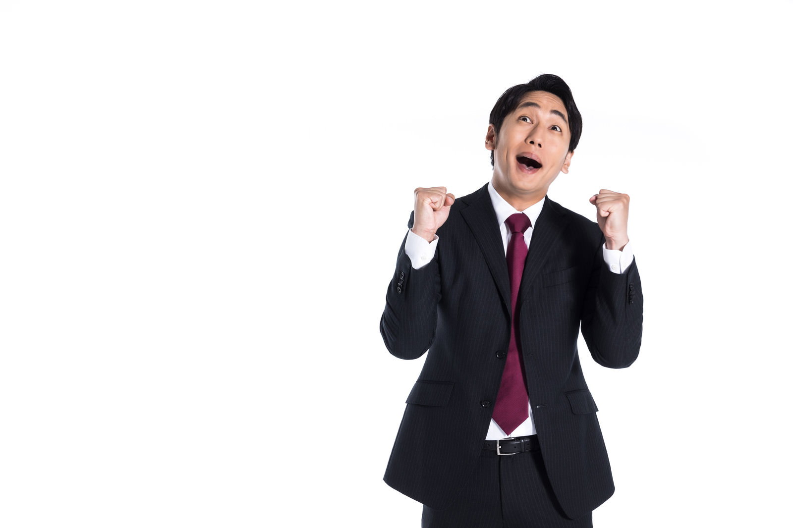 両拳を握り上げて上を向き、口を開けて喜びを表現するスーツ姿の男性［モデル：大川竜弥］