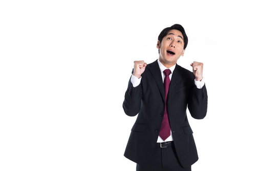 喜びに両拳を握り上げるスーツ姿の男性