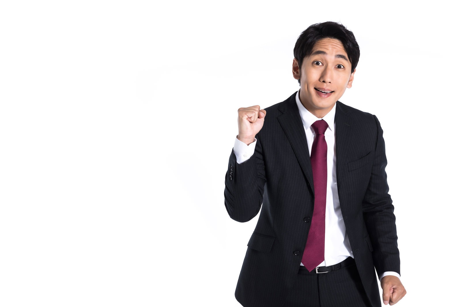 黒いスーツに赤いネクタイの会社員が拳を握ってガッツポーズ［モデル：大川竜弥］