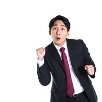 紺色スーツで拳を握りガッツポーズする会社員の写真