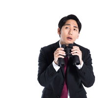 双眼鏡を持ち張り込み中の真剣な表情のサラリーマンの写真