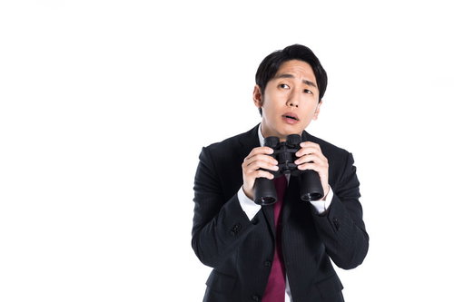 双眼鏡を持ち張り込み中の真剣な表情のサラリーマン