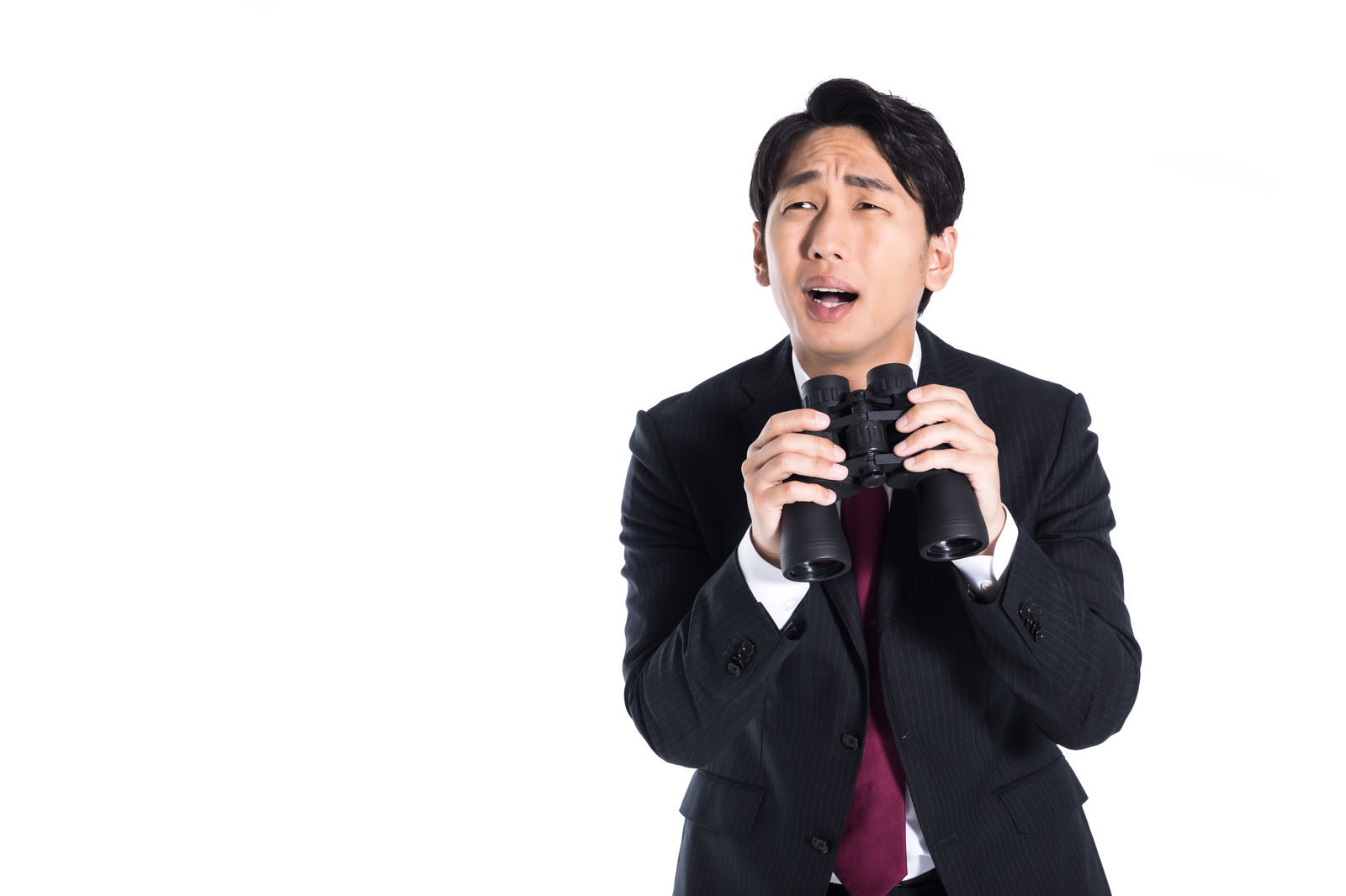 双眼鏡を両手で持ち唖然とした表情を見せるスーツ姿の男性［モデル：大川竜弥］