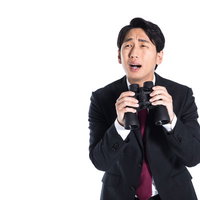 双眼鏡を持って唖然とする悲報を受けたスーツ姿の男性の写真