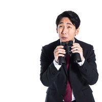 待ち伏せして双眼鏡を持ち微笑むストーカー男性の写真