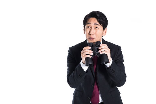 待ち伏せして双眼鏡を持ち微笑むストーカー男性