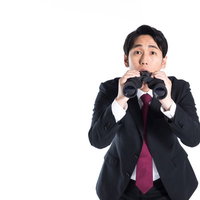 双眼鏡からひょっこり顔を出す黒いスーツの会社員男性の写真