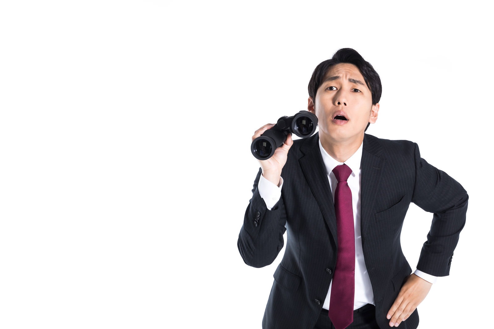 双眼鏡を持ち驚くスーツ姿の男性［モデル：大川竜弥］