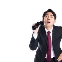 双眼鏡を使った内偵中のマトリ男性、スーツ姿で遠くを見つめるの写真