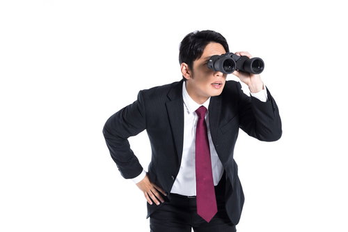 双眼鏡で何かを探すスーツ姿のエージェント