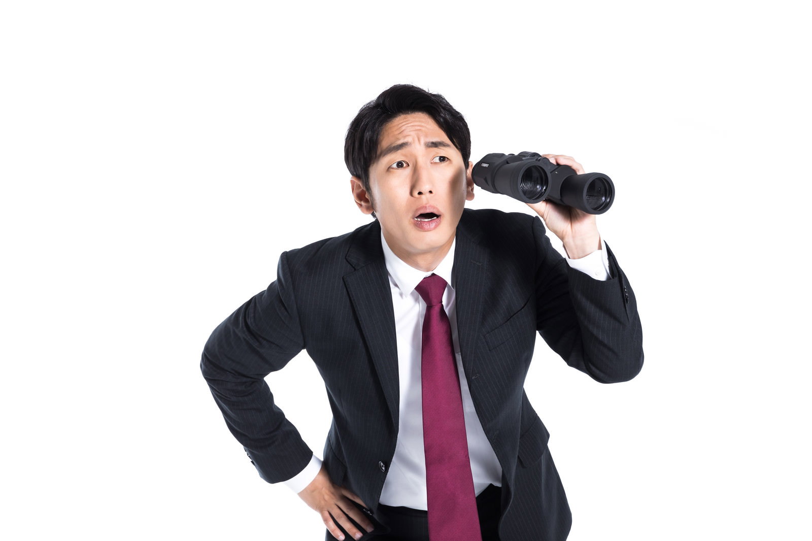 双眼鏡を手に持ち何かを探しているスーツ姿の会社員男性［モデル：大川竜弥］