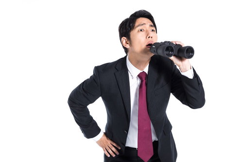 双眼鏡で遠くを見張る私服警官のスーツ姿の男性