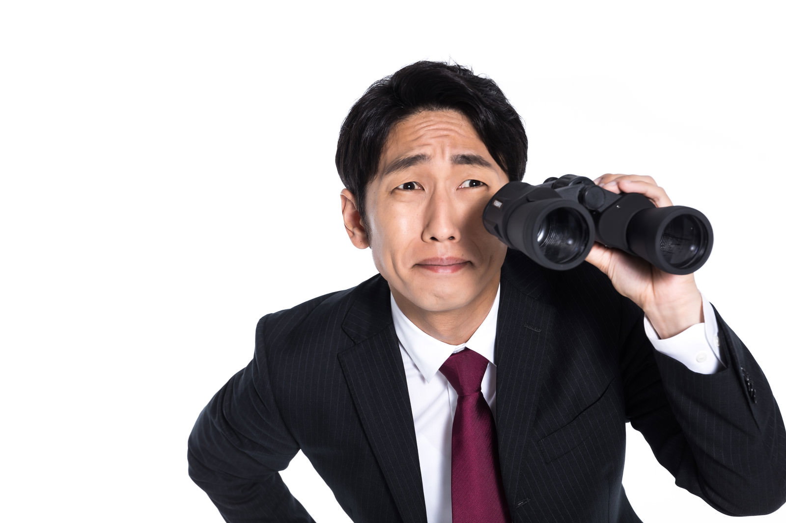 黒いスーツを着た男性が双眼鏡を両眼に当てて調査している［モデル：大川竜弥］
