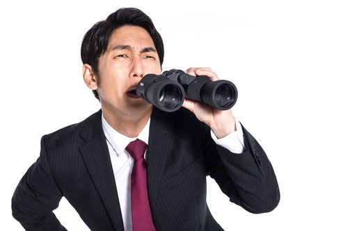 内偵中に対象を見失う探偵・双眼鏡で上空を見張る男性