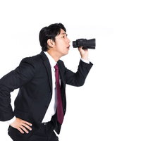 双眼鏡を持ってサボっている従業員を監視するリーダーの写真