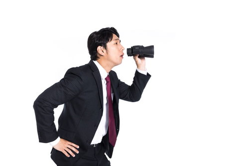 双眼鏡を持ってサボっている従業員を監視するリーダー