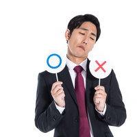 ○×札を持って迷うスーツ姿の男性の写真