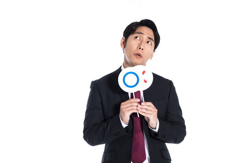 ○×クイズの正解を考えるスーツ姿の男性の判断
