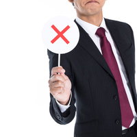 赤いバツマークを持つスーツ姿の男性の写真