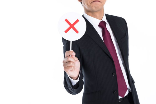 赤いバツマークを持つスーツ姿の男性