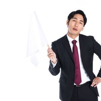 嫌々白旗を揚げるスーツ姿の会社員の写真