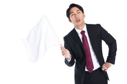 白旗を振って完敗を認める会社員、敗北感を表現する男性
