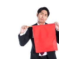 赤い旗を両手で掲げて危険を知らせる会社員の写真