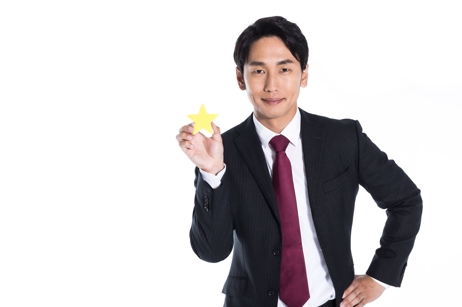 星マークを手に持つスーツ姿の男性が自信に満ちた表情で立っている［モデル：大川竜弥］