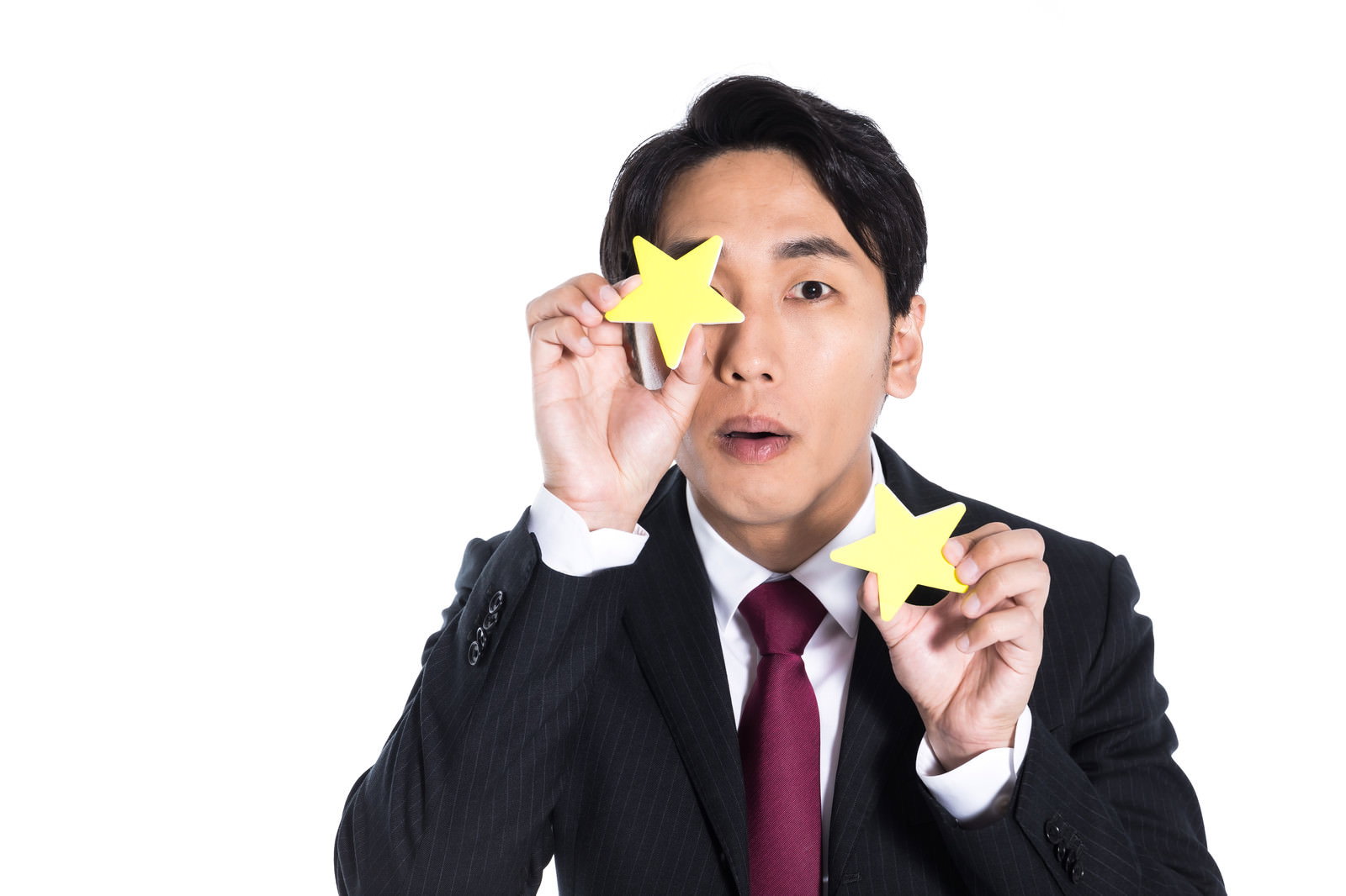 黄色い星シールを目の前にかざして評価を表現するスーツ姿の男性［モデル：大川竜弥］