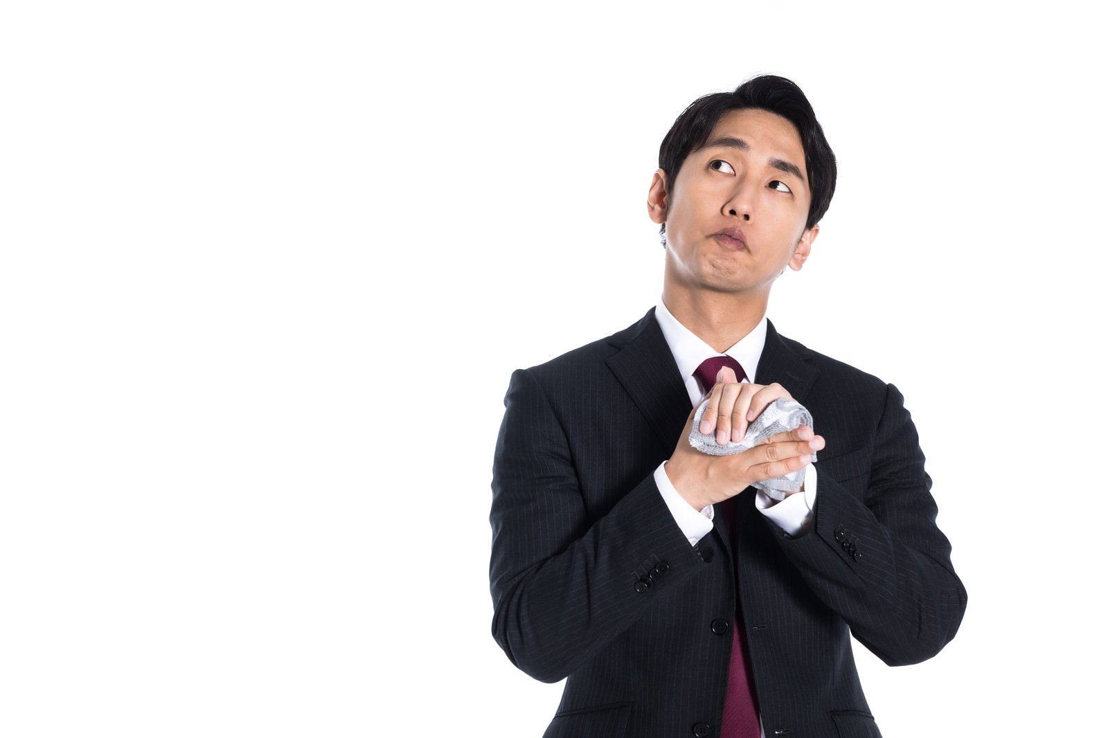 白いハンカチで手を拭きながら上を見上げて考え事をするスーツ姿の会社員男性［モデル：大川竜弥］