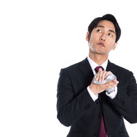 白いハンカチで手を拭きながら考え事をする会社員の写真