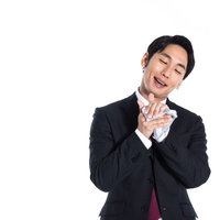 スーツ姿でハンカチを口元に当てる男性の写真
