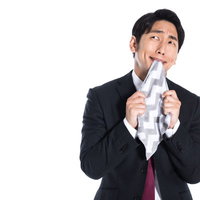 ハンカチを口に当てて上を向く悔しい男性会社員の写真