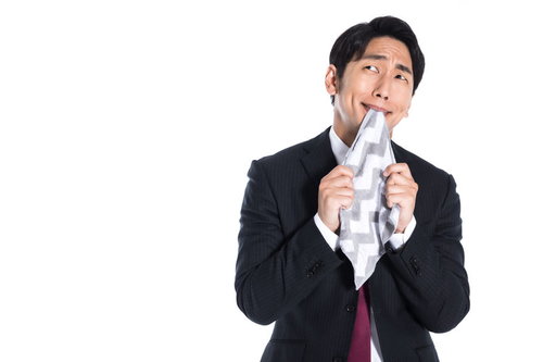 ハンカチを口に当てて上を向く悔しい男性会社員