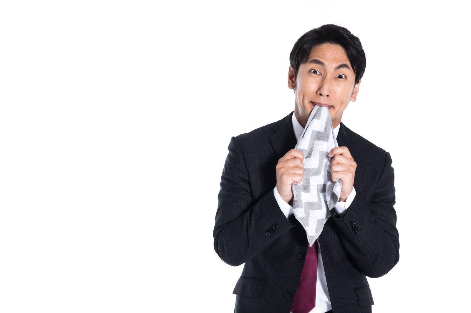 悔しくてハンカチを噛むスーツ姿の男性［モデル：大川竜弥］