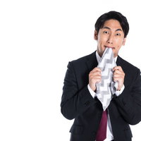 悔しくてハンカチを噛む男性の写真