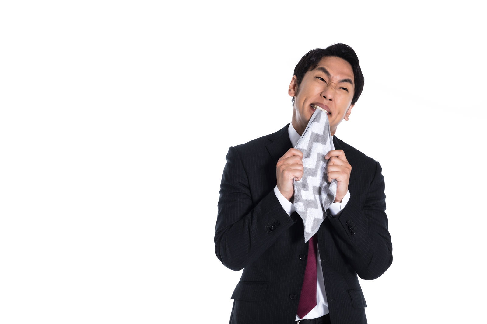 悔しそうにハンカチを咥えながら上を向く黒いスーツを着た男性［モデル：大川竜弥］