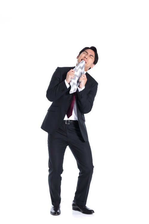 ハンカチを噛んで苛立つスーツ姿の男性