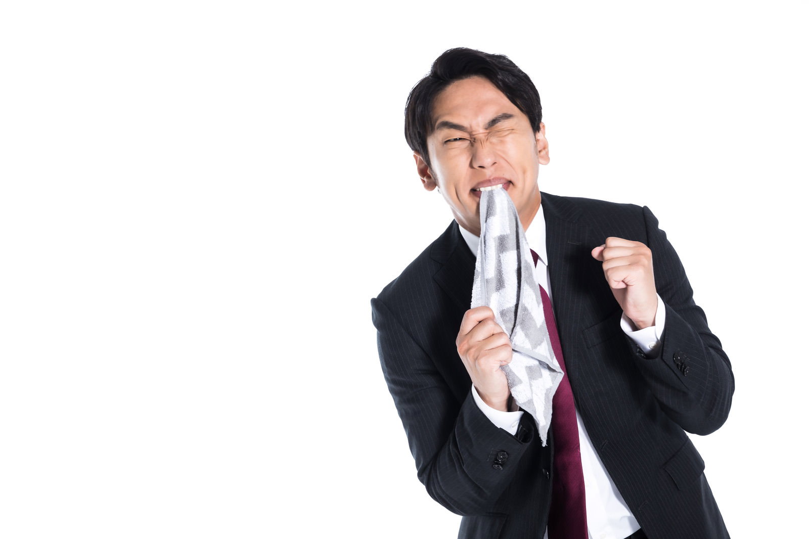 白いハンカチを口に咥えて歯を食いしばり、眉をひそめた悔しそうな表情のスーツ姿の男性［モデル：大川竜弥］
