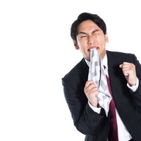 ハンカチを噛みしめて歯を食いしばる悔しい表情のビジネスマンの写真