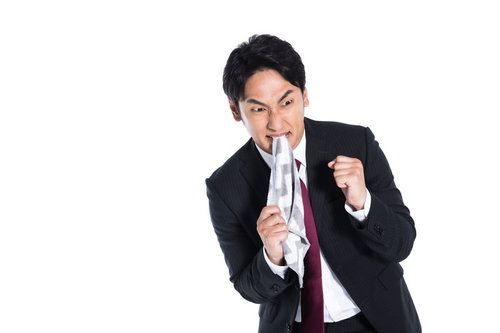 ハンカチを噛んで怒り爆発させるスーツ男性