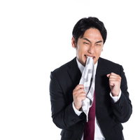 ハンカチを噛んで悔しさに発狂する男性の写真