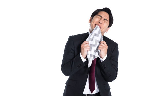 ハンカチを噛んで悔しさに耐えるビジネスマン