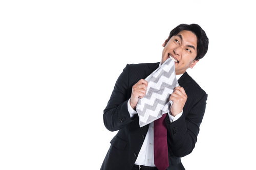 同期の出世に嫉妬し悔しさで悶々とするスーツの男性