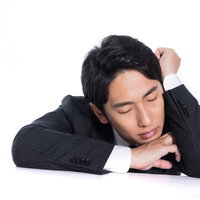 肘を立てて机に突っ伏す昼寝する会社員の寝落ち風景の写真