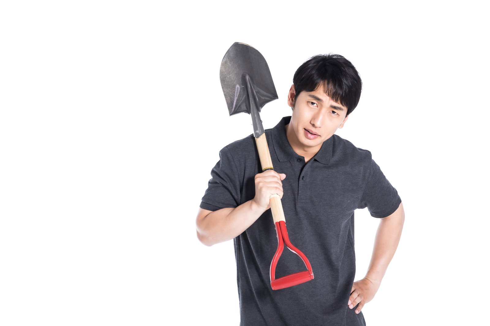 シャベルを肩にかけて自信満々にポーズを決める黒い作業着の男性［モデル：大川竜弥］