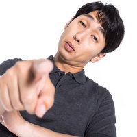 グレーシャツで憮然とした態度で指摘する男性の写真